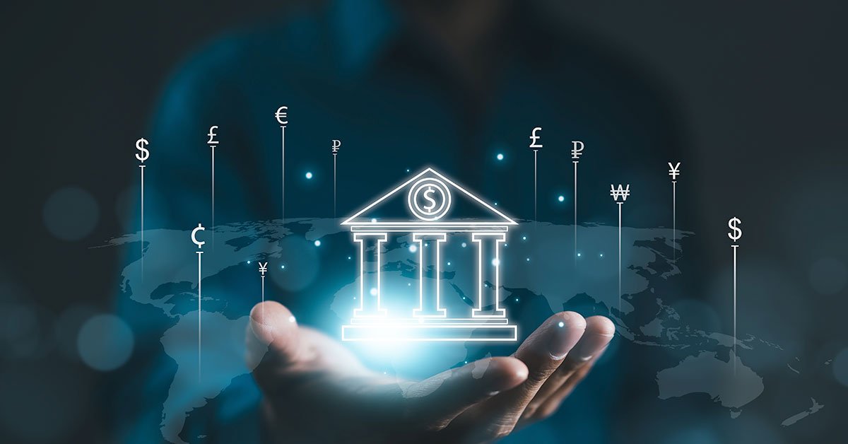 Hand holding a glowing digital icon of a central bank building surrounded by various global currency symbols over a world map background.