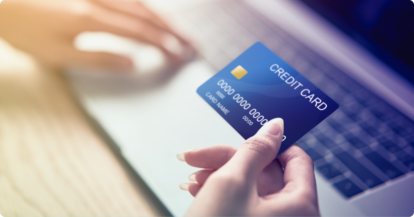 A person holding a blue credit card in front of a laptop during an online payment process